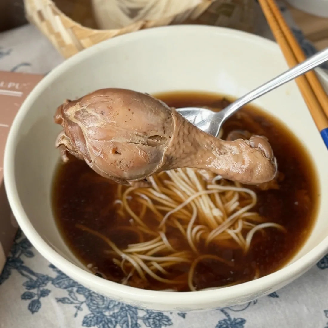 用汤匙夹起鸡腿，碗里是面线和深色的八珍鸡汤